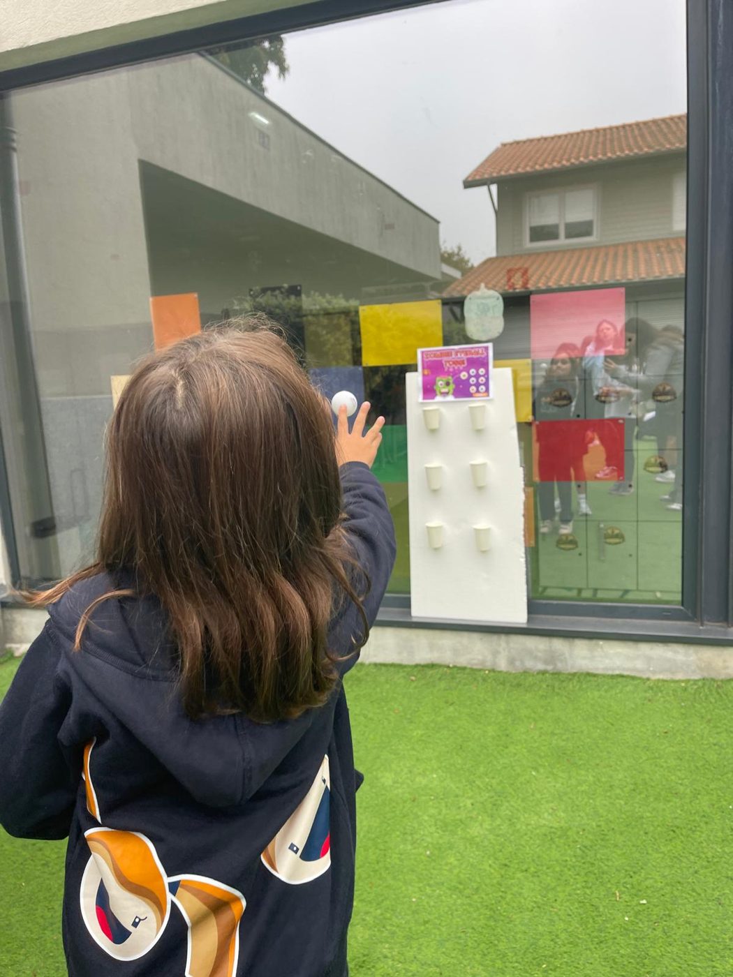 Criança a lançar uma bola num jogo de pontaria de Halloween