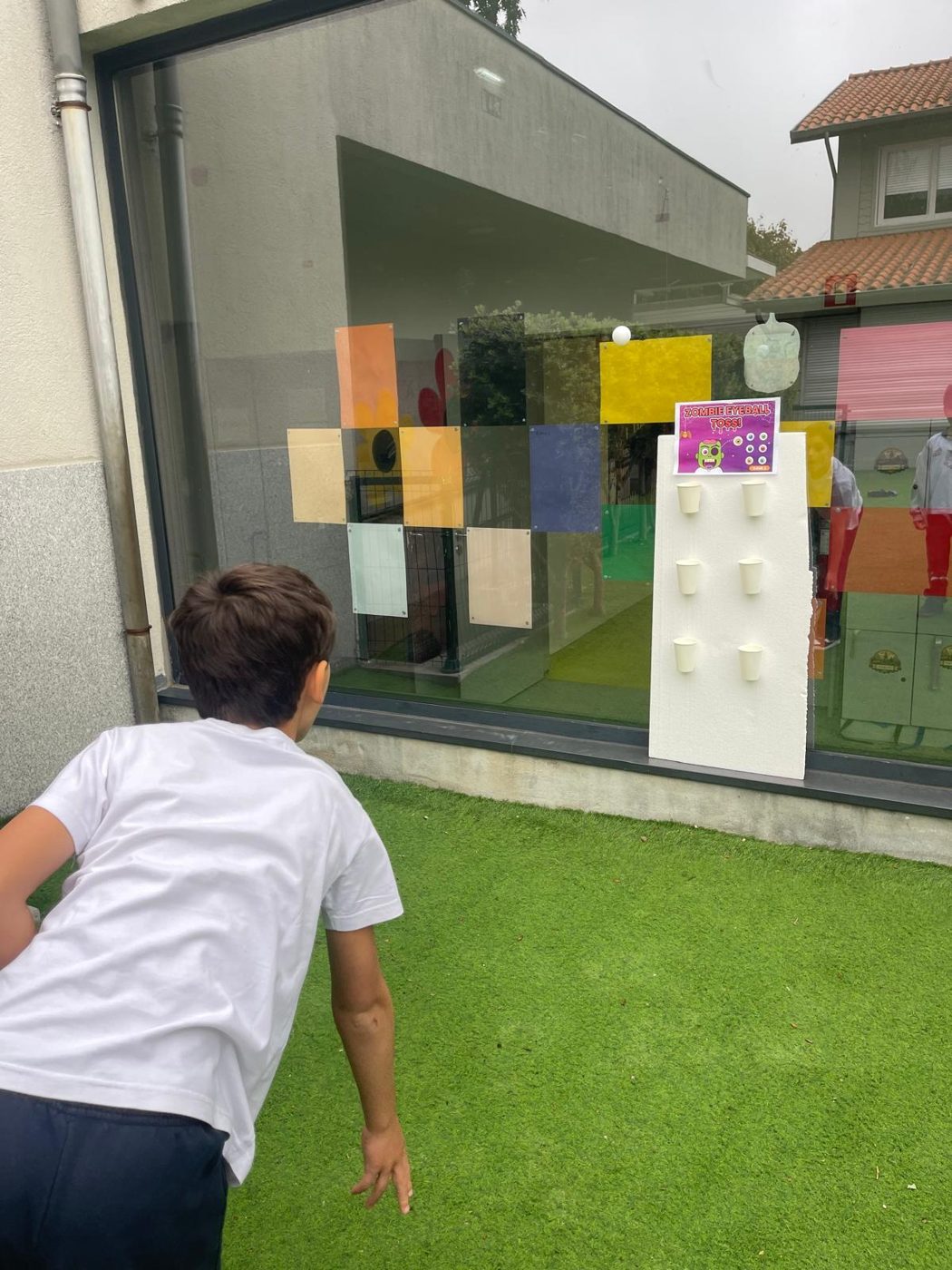 Criança a lançar uma bola num jogo de pontaria de Halloween, no recreio