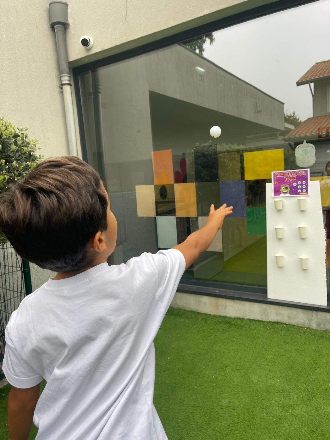 Criança a lançar uma bola num jogo de pontaria de Halloween