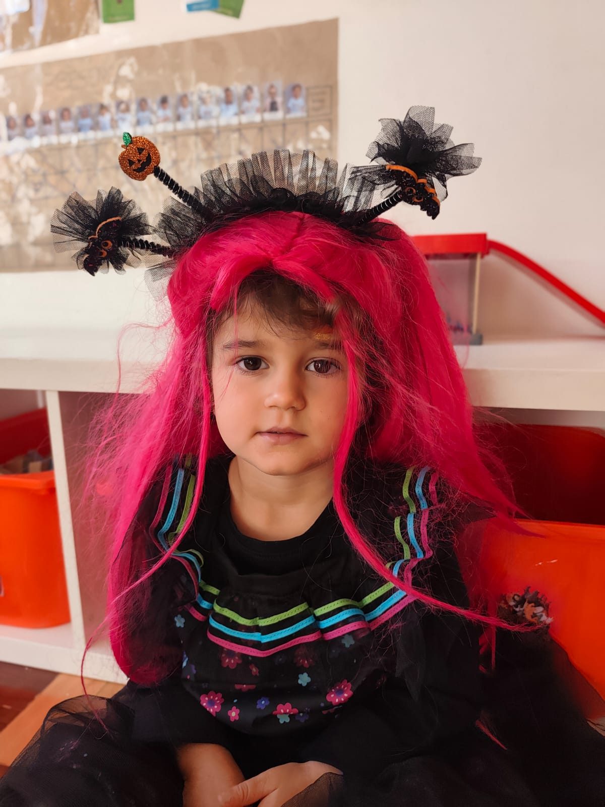 Criança com peruca cor-de-rosa e bandolete de aranha